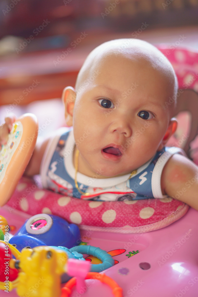 Asian infant baby boy sitting in a pink stroller and looking at the camera Asian infant baby boy sitting in a pink stroller and looking at the camera