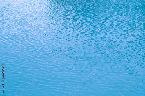 Blue water background. The calm surface of the sea. Ocean. Natural abstract background. Film grain and noise.