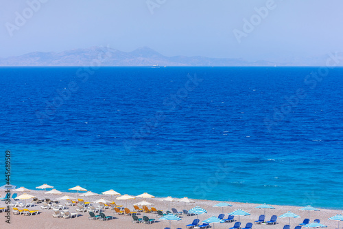 Colorful umbrellas and sunbeds on an empty beach resort - vacation concept on Greece islands in Aegean and Mediterranean seas