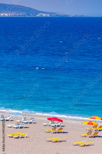 Fototapeta Naklejka Na Ścianę i Meble -  Colorful umbrellas and sunbeds on an empty beach resort - vacation concept on Greece islands in Aegean and Mediterranean seas