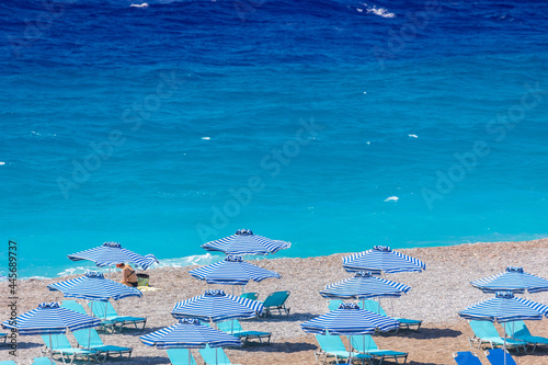 Colorful umbrellas and sunbeds on an empty beach resort - vacation concept on Greece islands in Aegean and Mediterranean seas