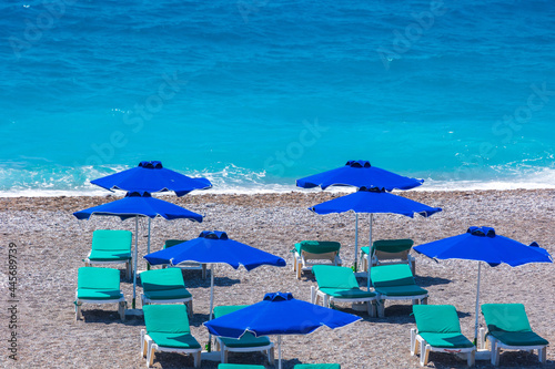 Colorful umbrellas and sunbeds on an empty beach resort - vacation concept on Greece islands in Aegean and Mediterranean seas