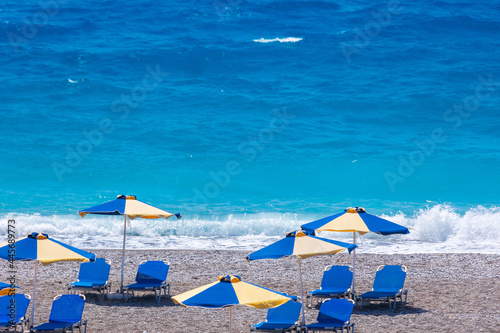 Colorful umbrellas and sunbeds on an empty beach resort - vacation concept on Greece islands in Aegean and Mediterranean seas