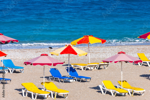 Colorful umbrellas and sunbeds on an empty beach resort - vacation concept on Greece islands in Aegean and Mediterranean seas