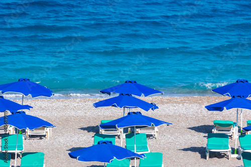 Colorful umbrellas and sunbeds on an empty beach resort - vacation concept on Greece islands in Aegean and Mediterranean seas