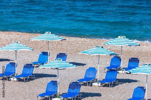 Colorful umbrellas and sunbeds on an empty beach resort - vacation concept on Greece islands in Aegean and Mediterranean seas