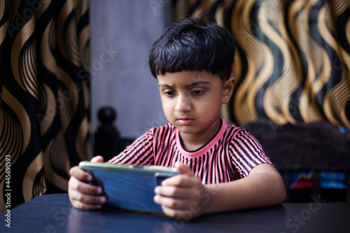 Asian kid attending online school using mobile phone, Online class concept Indian kid