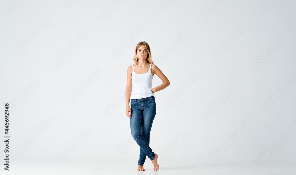 pretty woman in jeans posing fashion barefoot light background