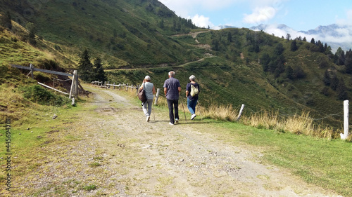 middle-aged people walking together. A man and two women having a health activity in the nature (italian Alps mountains)
