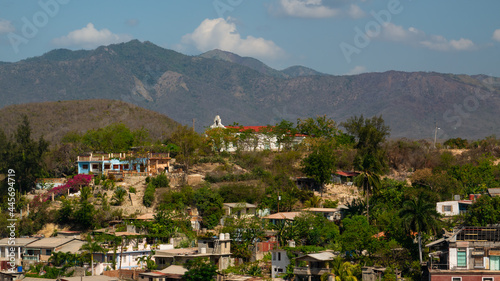 Cuban poor colorful village with church on the hill near city Santiago de Cuba 