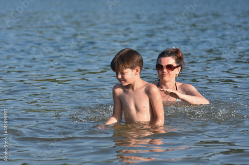 40 Years old Mom play with son in water. Cheerful child splashing and enjoy in water with his mother