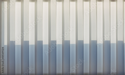 Abstract geometric vertical lines white and gray gradient color. Repeating pattern  background texture  design of striped lines. Blinds illuminated by the sun  close-up.