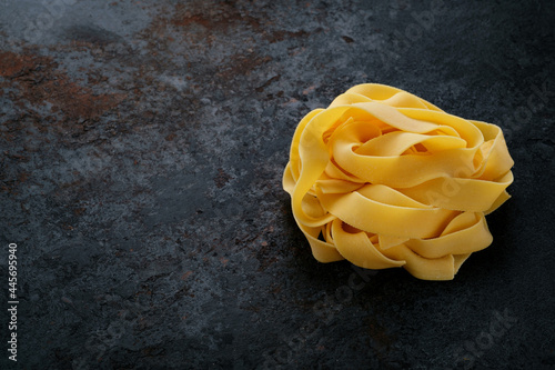 Raw pappardelle pasta on a black stone background. Fresh uncooked egg pasta, copy space photo
