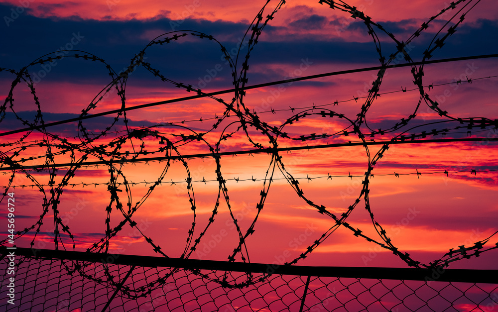beautiful sunset behind the fence with barbed wire