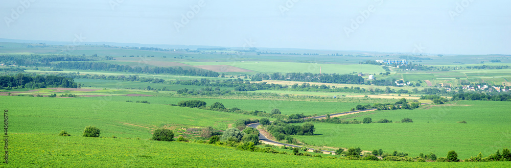 Asphalt road through a field against the background of a village in Ukraine Asphalt road through a field against the background of a village in Ukraine