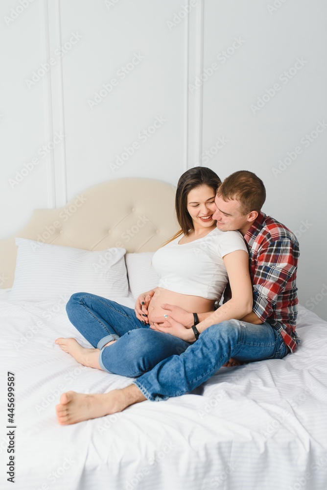 Young pregnant woman with husband on sofa in room Young pregnant woman with husband on sofa in room