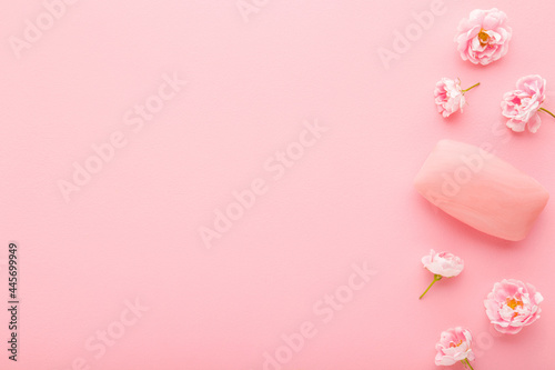 Natural hand soap and beautiful roses on light pink table background. Pastel color. Care about clean and soft body skin. Daily beauty product. Closeup. Empty place for text or logo. Top down view.