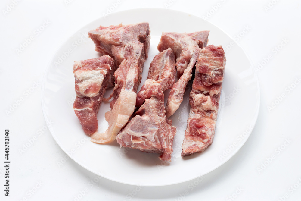 Raw pork bone in white plate on white background.