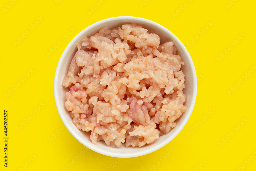 Minced meat of chicken fillet in white bowl on yellow background. Minced meat of chicken fillet in white bowl on yellow background.