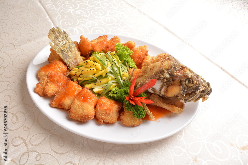 deep fried whole grouper fish seafood with sweet and sour sauce & mango salad in the middle asian halal menu
