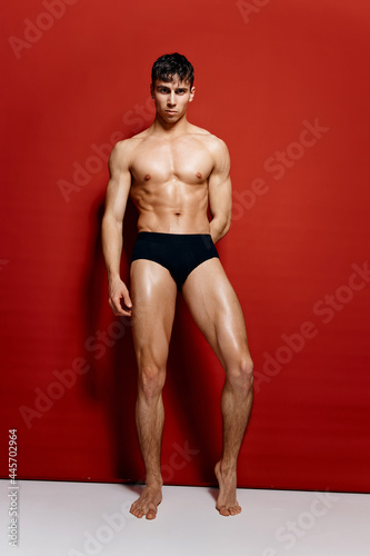 sexy bodybuilder with a pumped-up torso on a red background fitness model