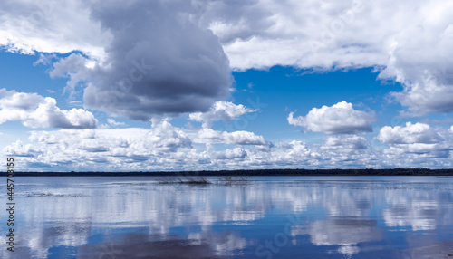 Dramatic view of the water surface of the lake reflecting the sky with clouds in cloudy cool weather