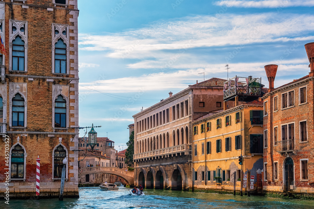 Beautiful view of Venetian landscape. Waterfront palaces, bridges, and boats. Corner of Ca' Foscari and side rio by Grand Canal, Venice, Italy.