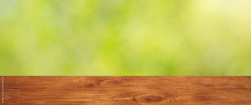 Background with blurred green leaves and empty wooden planks in the foreground. Background with blurred green leaves and empty wooden planks in the foreground.