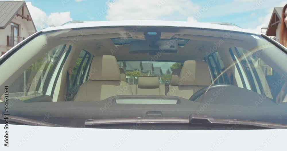 Mother and daughter opens car door and getting into a car, fasten seat belts. Car's interior. Front view.
