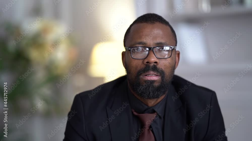portrait of a sad and tired bearded African-American man in glasses and a dark suit with a tie portrait of a sad and tired bearded African-American man in glasses and a dark suit with a tie