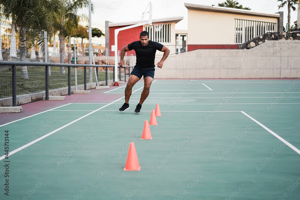 Hispanic man doing speed and agility cone drills workout session outdoors - Focus on man face Hispanic man doing speed and agility cone drills workout session outdoors - Focus on man face