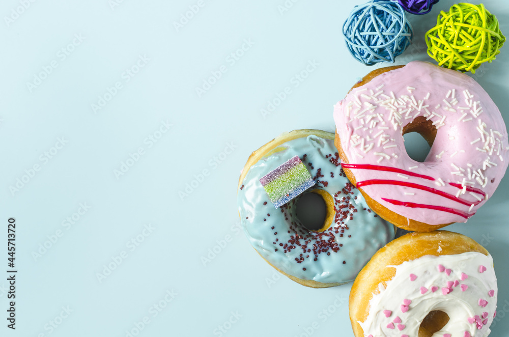 Fresh donuts with colored glaze and decor on a blue background of the mine space. Colorful donuts close-up