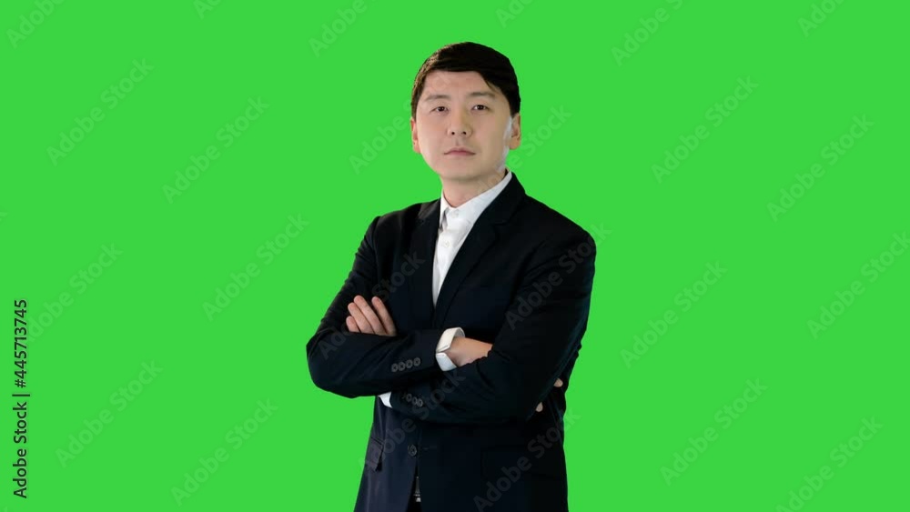 Asian man stands adjusting his suit and crossing arms on a Green Screen, Chroma Key. Asian man stands adjusting his suit and crossing arms on a Green Screen, Chroma Key.