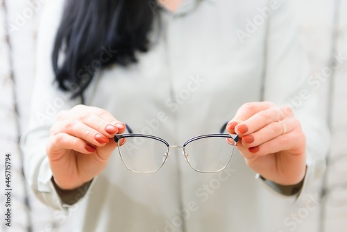 Closeup of optometrist, optician giving glasses to try