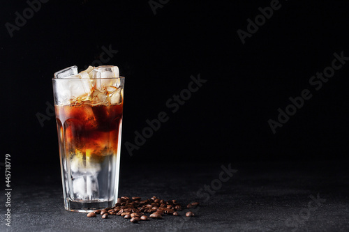 Cold drink with espresso and tonic in glass on black background