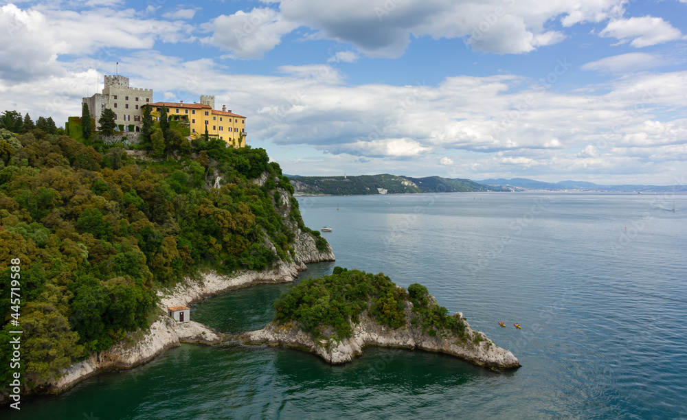 Castle of Duino on the rocky promontory on the Adriatic coast near Trieste, Italy, with the city skyline far in the background