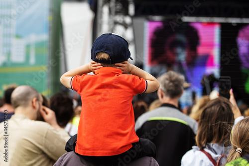 Photography A child at a street concert covers his ears due to loud music