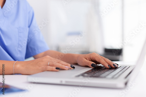 Close up of medical specialist typing on laptop in hospital office. Health practitioner searching in hospital database using laptop in hospital cabinet  keyboard  job.