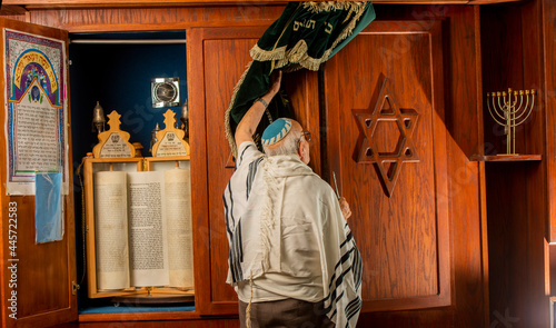 an older jewish man in front of a bible scroll in a synagogue