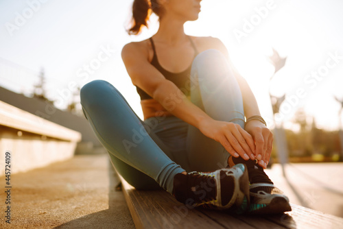 Young fitness woman exercising and stretching outdoors in the morning. Fit healthy athlete is doing workout on the street. Sport  Active life.