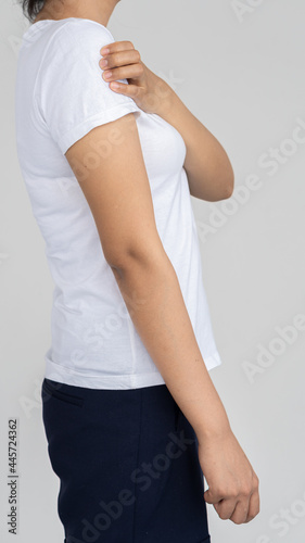 Woman with shoulder pain and yoke holding hands and white background, medical concept