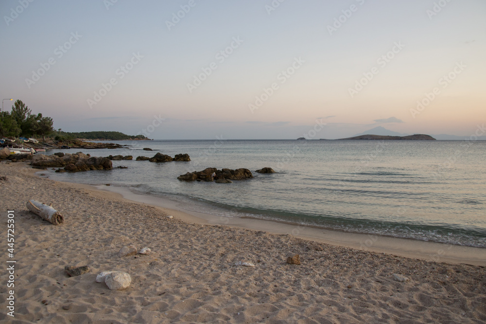 Small peaceful beach at sunset, beautiful seascape, boats in the background, travel destination, summer vacation, village Astris, island Thasos, Greece