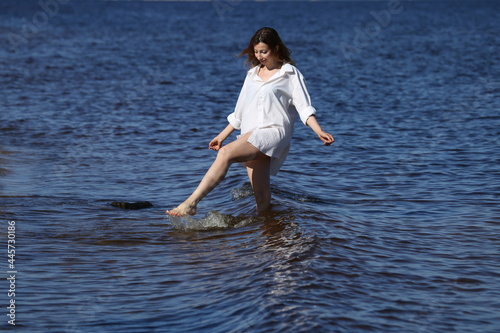 Pretty woman in white shirt playing with water in the sea