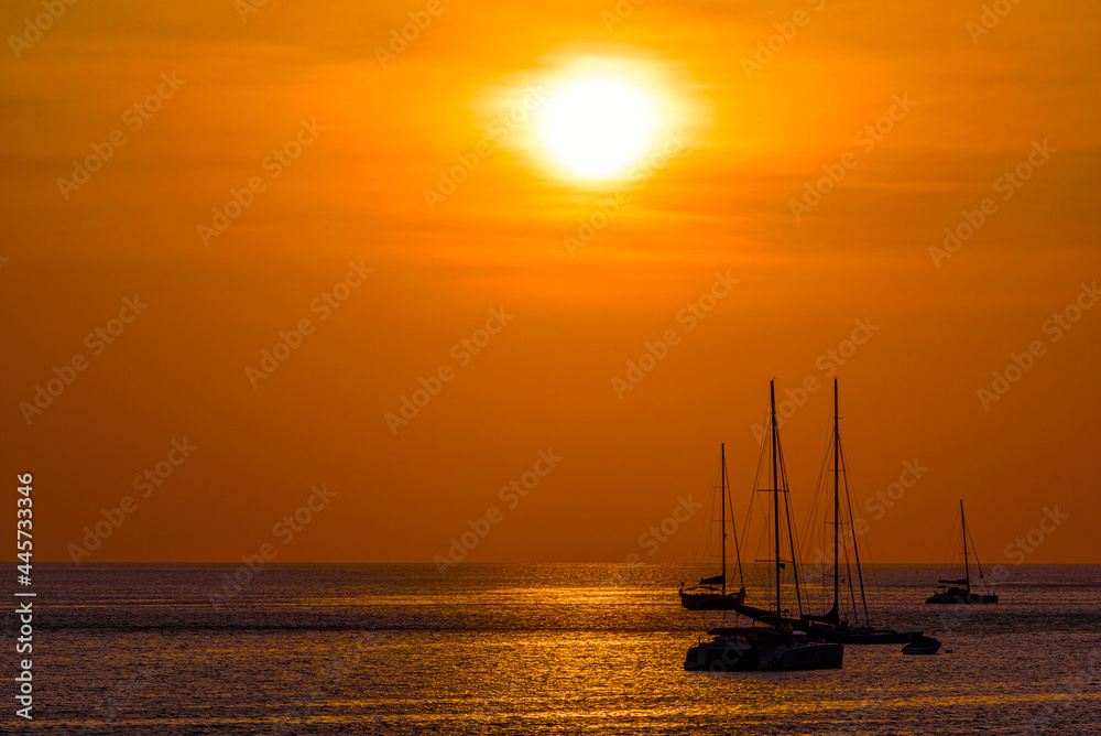 Silhouette of boat on sea beach with sunset background in Phuket Island, Thailand