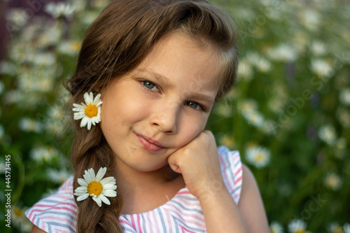 Portrait of a happy little girl with a bouquet of field daisies on a summer day at sunset.