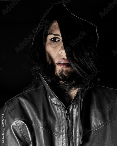 portrait of serious dark-haired woman in leather hooded jacket