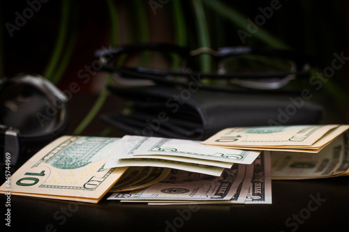Dollar bills in a wallet and on a dark background.