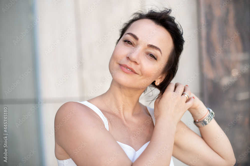 close-up adult attractive woman looking at the camera and smiling straightening hair close-up adult attractive woman looking at the camera and smiling straightening hair