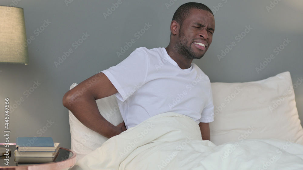 Exhausted Young African Man having Back Pain in Bed Exhausted Young African Man having Back Pain in Bed