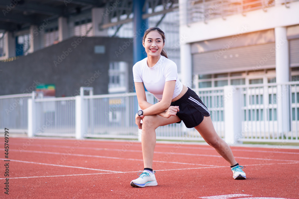 A young beautiful Asian woman in sports outfits doing stretching before workout outdoor in the park in the morning to get a healthy lifestyle. Healthy young woman warming up outdoors